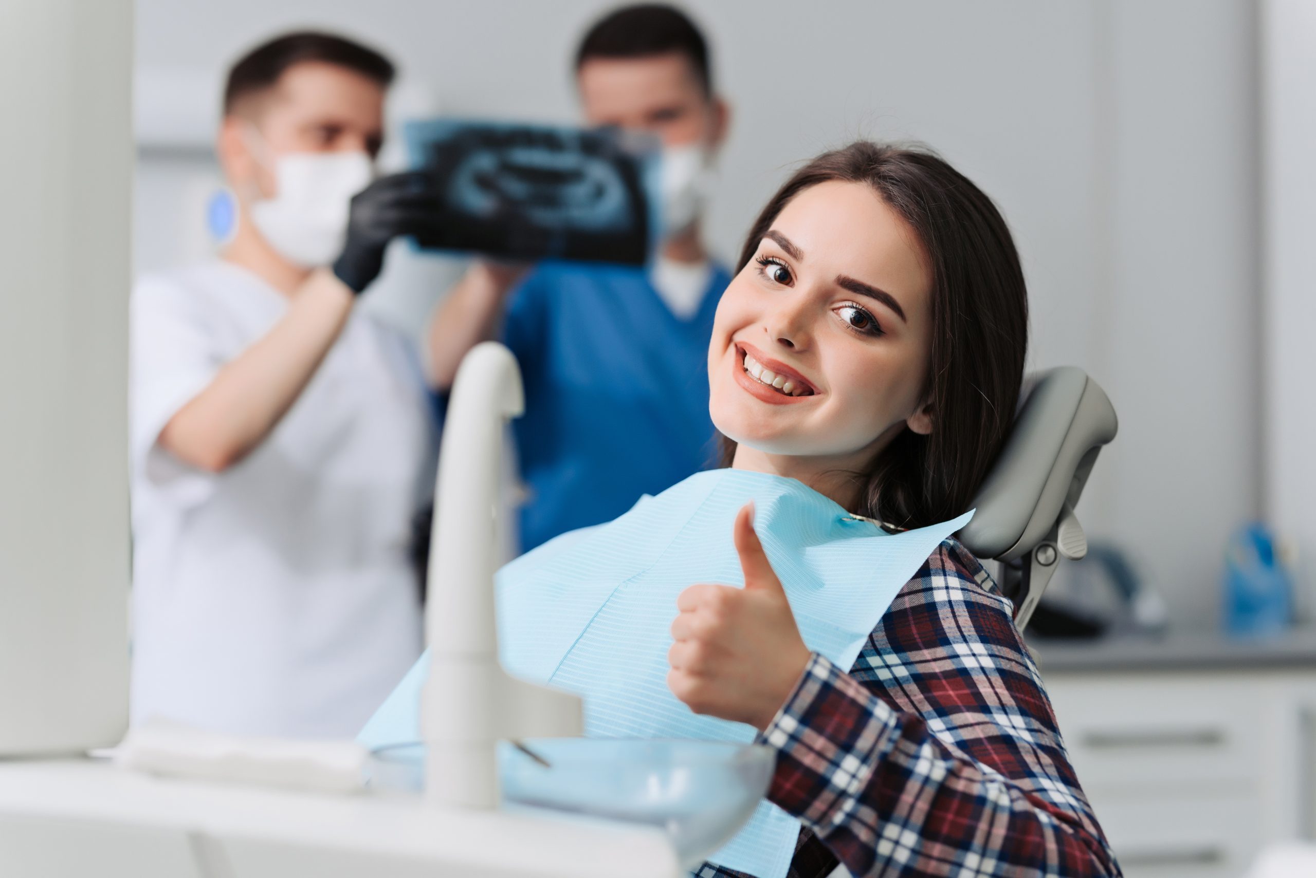 portrait of patient giving thumb up at dentist office with denti